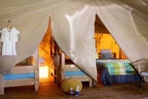 Eine Zelthütte mit Bett, Tisch und Stuhl.