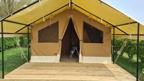 Uma tenda com plataforma de madeira, estrutura de metal e toldo amarelo.