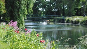 A serene garden with a pond, a bridge, and lush greenery. - ZEcamping 3 étoiles toboggans dog friendly locatif 5m2 4 pers (Quinéville)