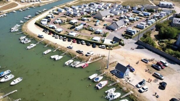 An aerial view of a marina with boats docked, a sandy beach, and a row of buildings. - ZEcamping 3 étoiles toboggans dog friendly locatif 5m2 4 pers (Quinéville)
