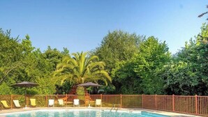 A swimming pool with lounge chairs and umbrellas, surrounded by a fence and trees. - ZEcamping 3* piscine pet friendly bien-être locatif 24m2 5 pers (Urt)