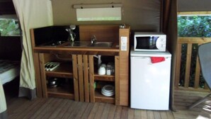 A compact kitchenette with a microwave, sink, and storage shelves. - ZEcamping 3* piscine pet friendly bien-être locatif 24m2 5 pers (Urt)