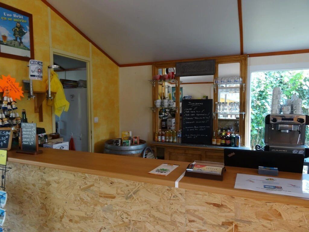 Una zona de bar con mostrador de madera, menú en una pizarra y máquina de café.