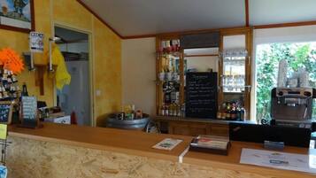 Una zona de bar con mostrador de madera, menú en una pizarra y máquina de café.