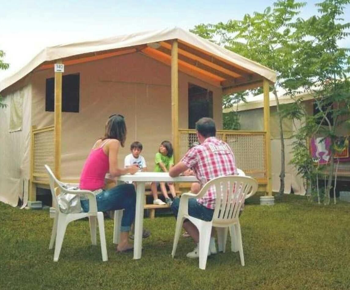 Eine Familie speist an einem Tisch im Freien unter einem Zelt.