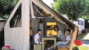 A tent with a table and chairs, a bicycle, and a small stool. - ZEcamping animé espace aquatique pet friendly locatif 17m2 4 pers (Le Château-d'Olonne)