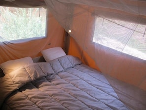 A bed with a canopy, a window, and a wall-mounted light.