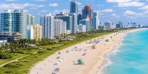 A coastal cityscape with high-rise buildings, a sandy beach, and a clear blue sky. - Tropical Getaway~Heated Pool~MiniGolf~BBQ~Pool table~Near FIFA World Cup Stadium (Fort Lauderdale)
