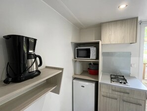 A compact kitchenette with a coffee maker, microwave, refrigerator, and gas stove. - ZEcamping 4* piscine club enfant - mobil-home 18m2 sanitaires communs (Proissans)