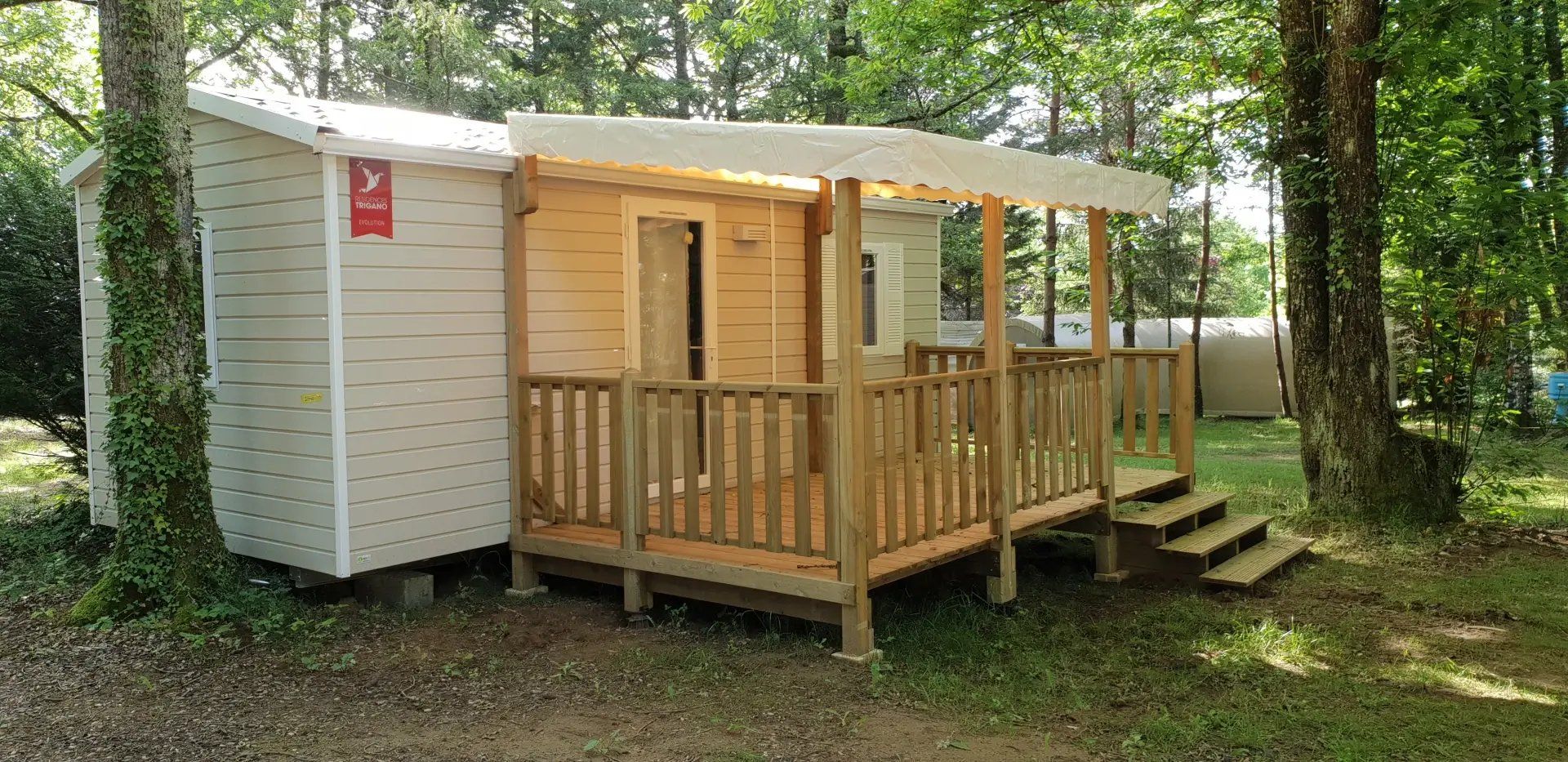 A small wooden cabin with a porch and a door, surrounded by trees.