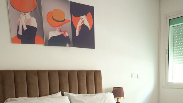 Ein Bett mit einer weiß-blauen Steude, einem braunen Kopfteil und einem weißen Kopfkissen.