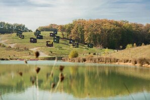 A series of small cabins on a hillside near a body of water. - ZEcamping 4* familial piscine chauffée roulotte BBQ (Estipouy)