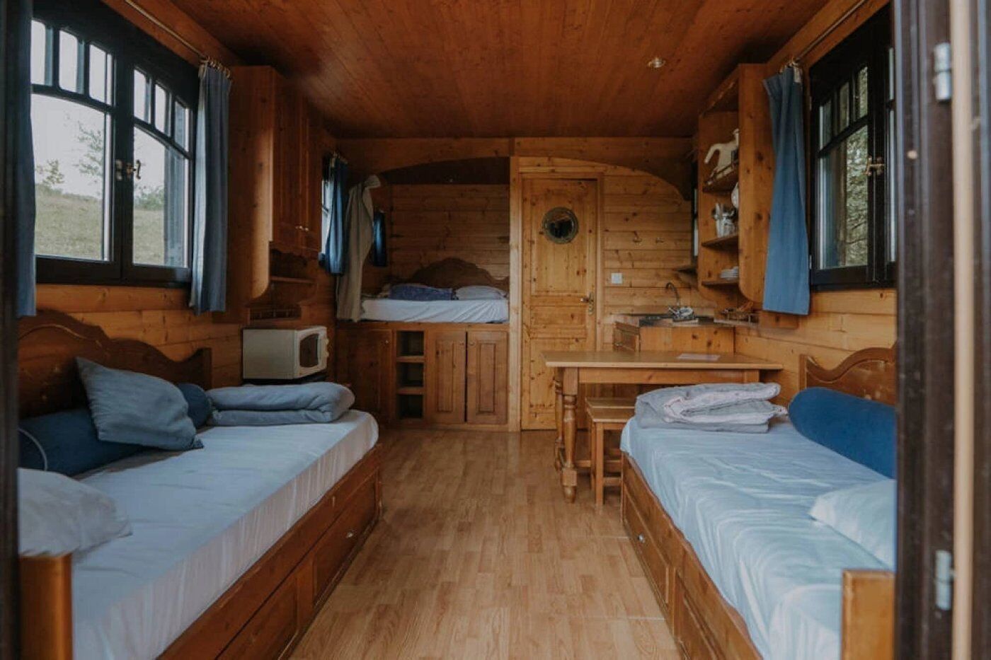 A cabin with two beds, a small table, and a microwave.
