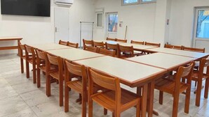 A conference room with multiple tables and chairs, a large flat-screen TV, an air conditioning unit, and windows with views. - ZEcamping 2* dog friendly locatif 2 pers (Angicourt)