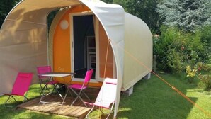 Un espace extérieur abrité, doté d’une table et de chaises, d’une petite entrée et aménagé comme un jardin.