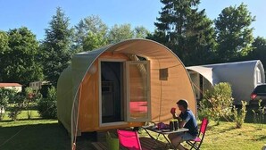 Un camping-car composé d’une seule pièce, doté d’une porte coulissante, d’une table et de chaises à l’extérieur.