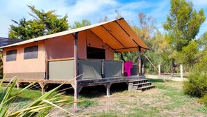 Einstöckiges Wohnmobil mit überdachter Veranda, flachem Dach und kleiner Terrassenfläche.