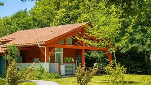 A house with a red roof, wooden structure, and a gravel path leading to it.