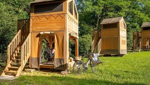 A wooden cabin with a porch, a bicycle, and a person sitting outside.