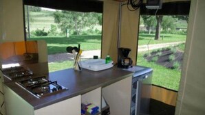 A kitchenette with a gas stove, coffee maker, and a window with a view of a grassy area.
