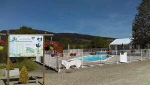 A pool area with a fenced deck, a signboard, and a building in the background.
