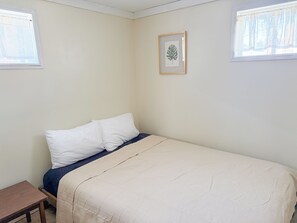 Ett sovrum med en säng, ett litet bord och en inramad tavla på väggen.