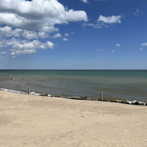 A beach with a sandy shore and a wooden barrier. - Escape to your private Lake Huron retreat with 6 fully equipped cottages, 13 bedrooms, and 6 bathrooms, perfect for family reunions, weddings, retreats, and group getaways. (Iosco County)