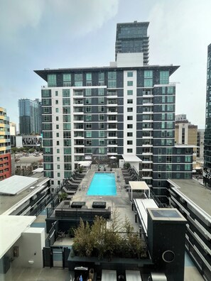 A modern building with a rooftop pool, multiple balconies, and a clear sky. - Classy 1-bedroom condo in Little Italy, Downtown San Diego, with AC, gym, valet (San Diego)