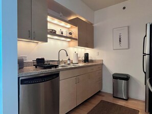 A modern kitchen with stainless steel appliances, a dishwasher, and a coffee maker. - Classy 1-bedroom condo in Little Italy, Downtown San Diego, with AC, gym, valet (San Diego)