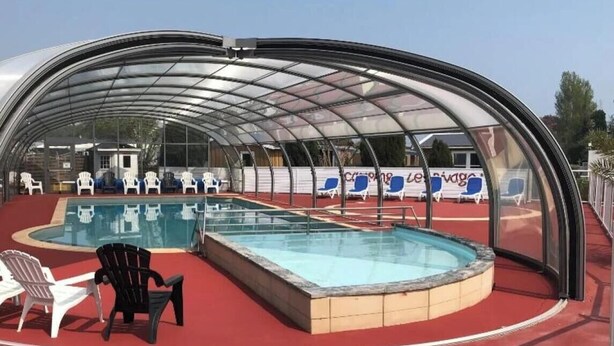 Una piscina techada con sillas de descanso y piso rojo.