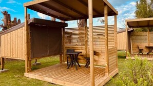 Una estructura de madera al aire libre con un área de estar cubierta y una mesa.