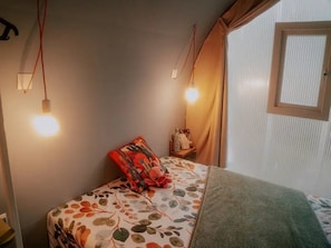 A bedroom with a bed, a nightstand, a lamp, and a window with curtains. - ZEcamping 3 étoiles familial piscine chauffée mobil-home 16m2 (Florac)