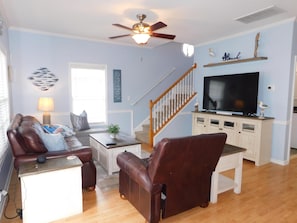 A living room with a sofa, armchair, coffee table, TV, and a ceiling fan. - Ocean Lakes Site 1705 "A Mermaids Treasure" 4bed/3bath | golf cart (Myrtle Beach)
