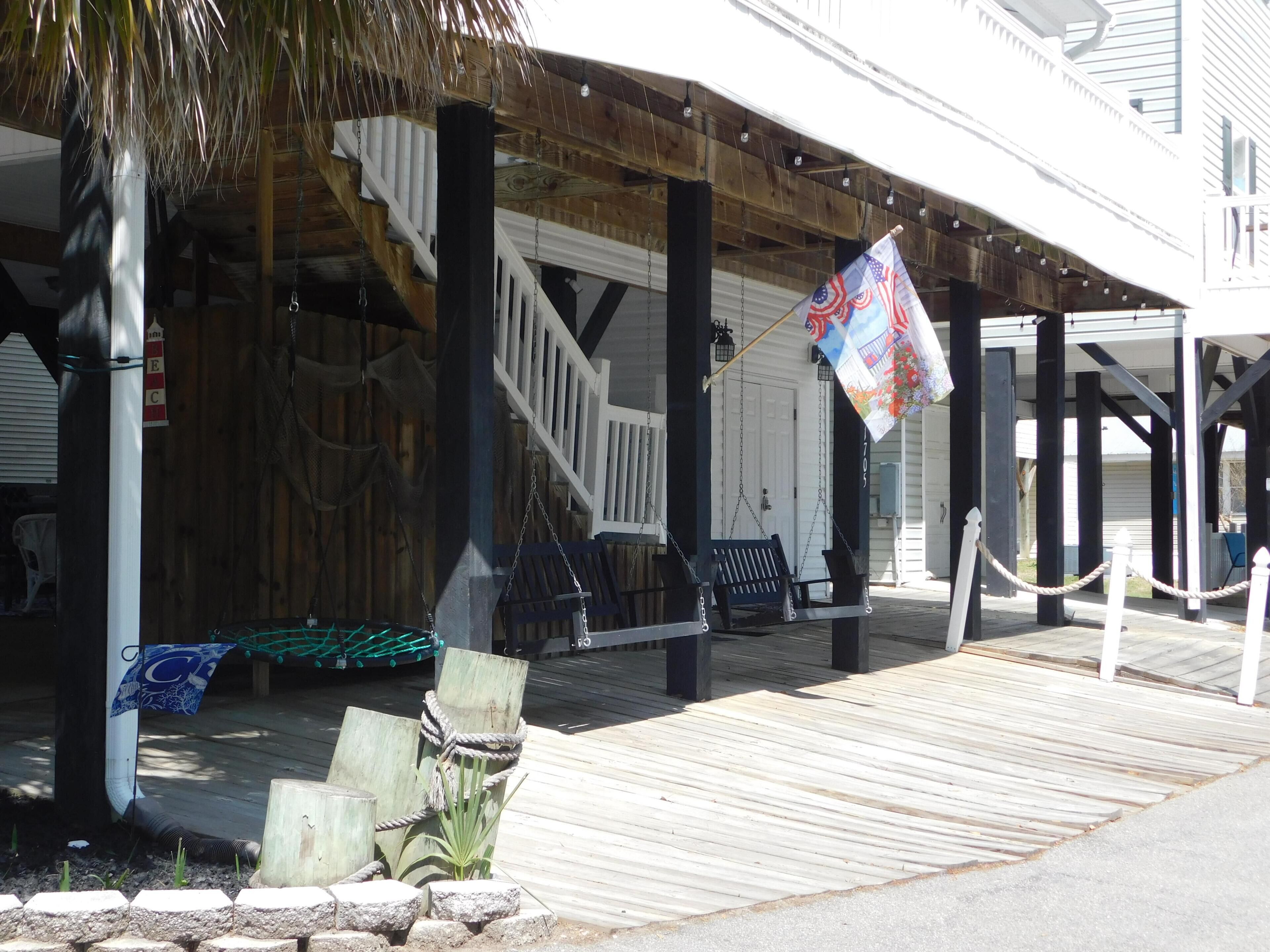 A wooden deck with a bench, a rope-bound chair, and a flag.