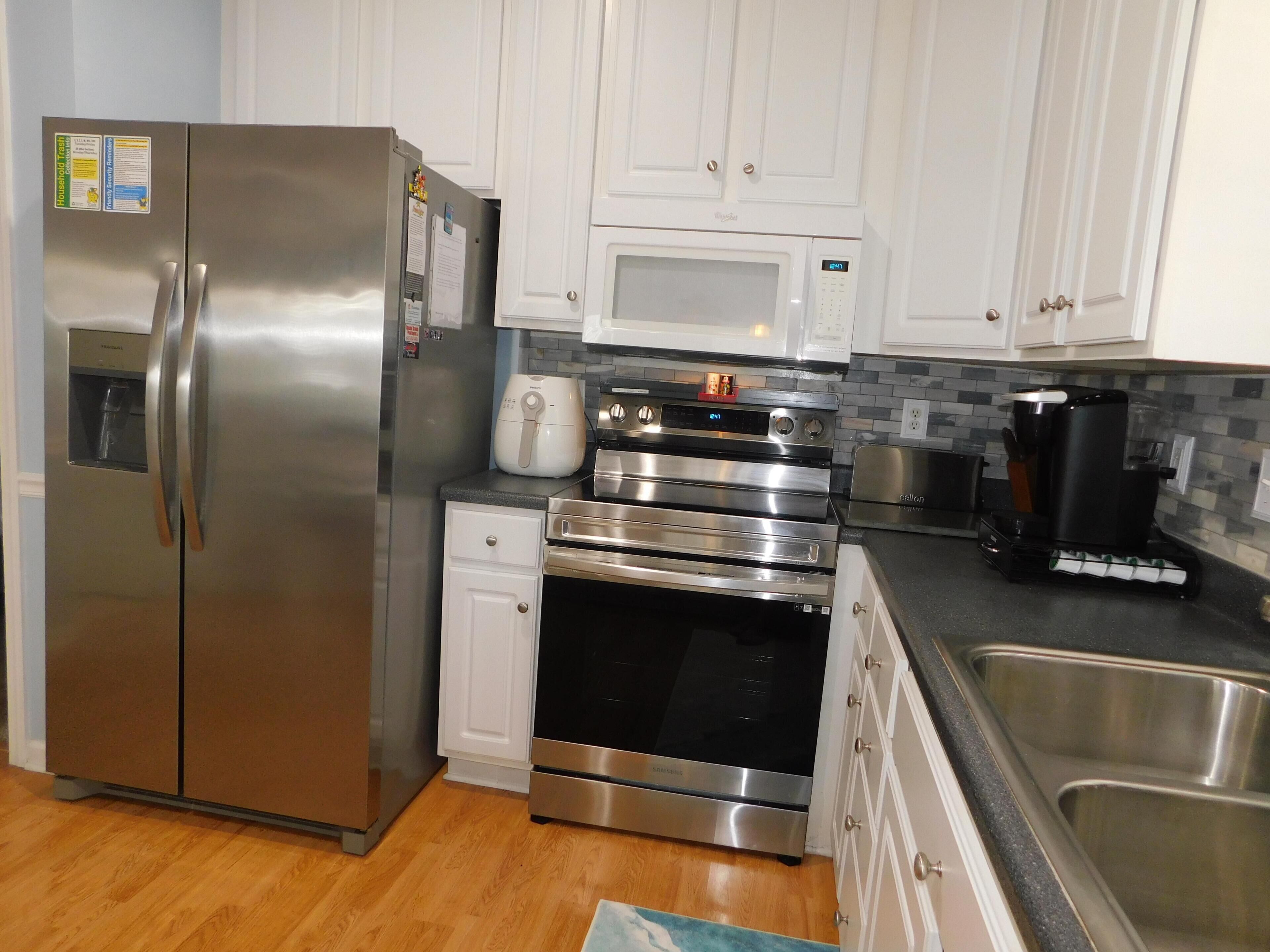 A modern kitchen with stainless steel appliances, white cabinetry, and a tiled backsplash.