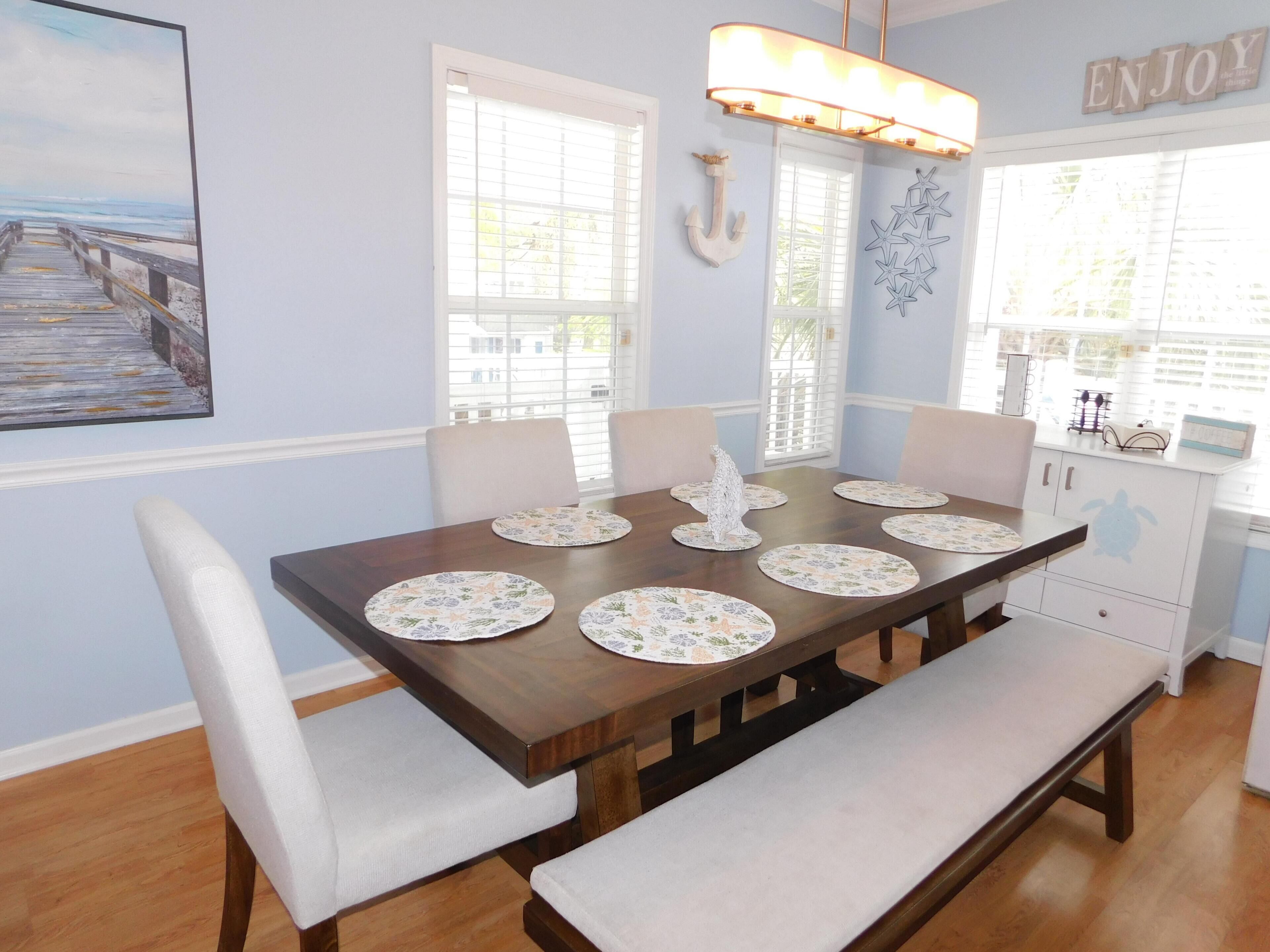 A dining area with a wooden table, white cushioned chairs, and a bench.