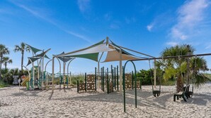 A beach playground with play structures, shaded areas, and palm trees. - Ocean Lakes Site 1705 "A Mermaids Treasure" 4bed/3bath | golf cart (Myrtle Beach)