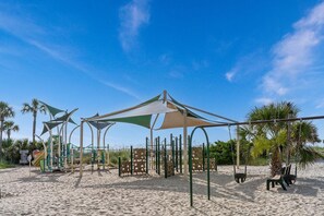 A beach playground with play structures, shaded areas, and palm trees. - Ocean Lakes Site 1705 "A Mermaids Treasure" 4bed/3bath | golf cart (Myrtle Beach)