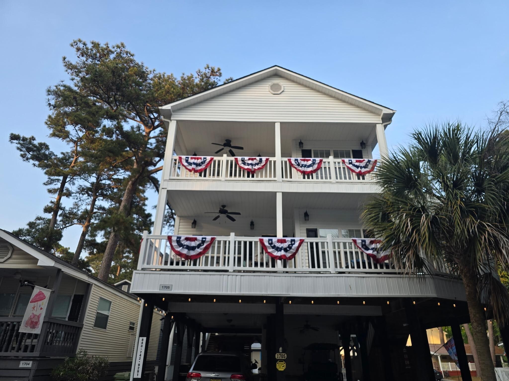 A two-story building with balconies, a covered parking area, and a flag decoration.