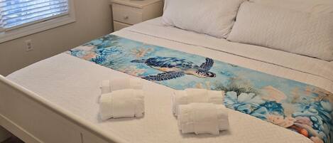 A bedroom with a bed, a nightstand, a lamp, and wall decorations including starfish and birds.