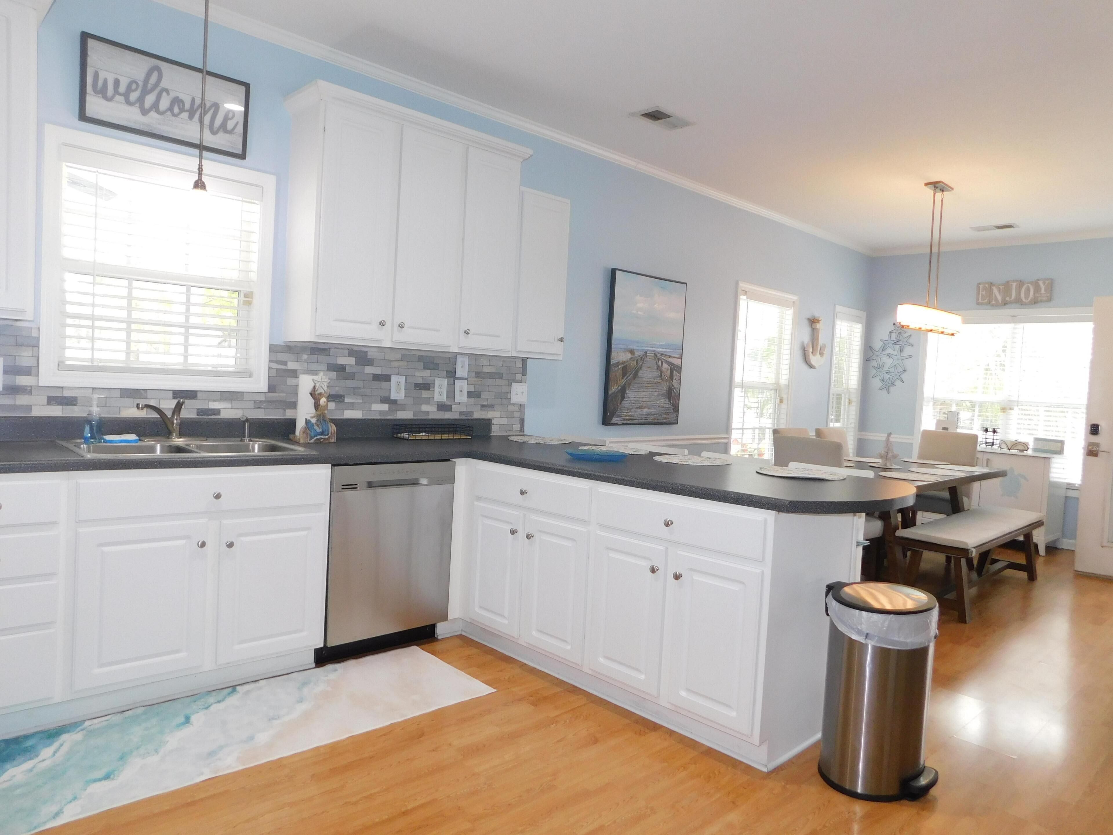 A modern kitchen with white cabinets, a stainless steel dishwasher, and a granite countertop.