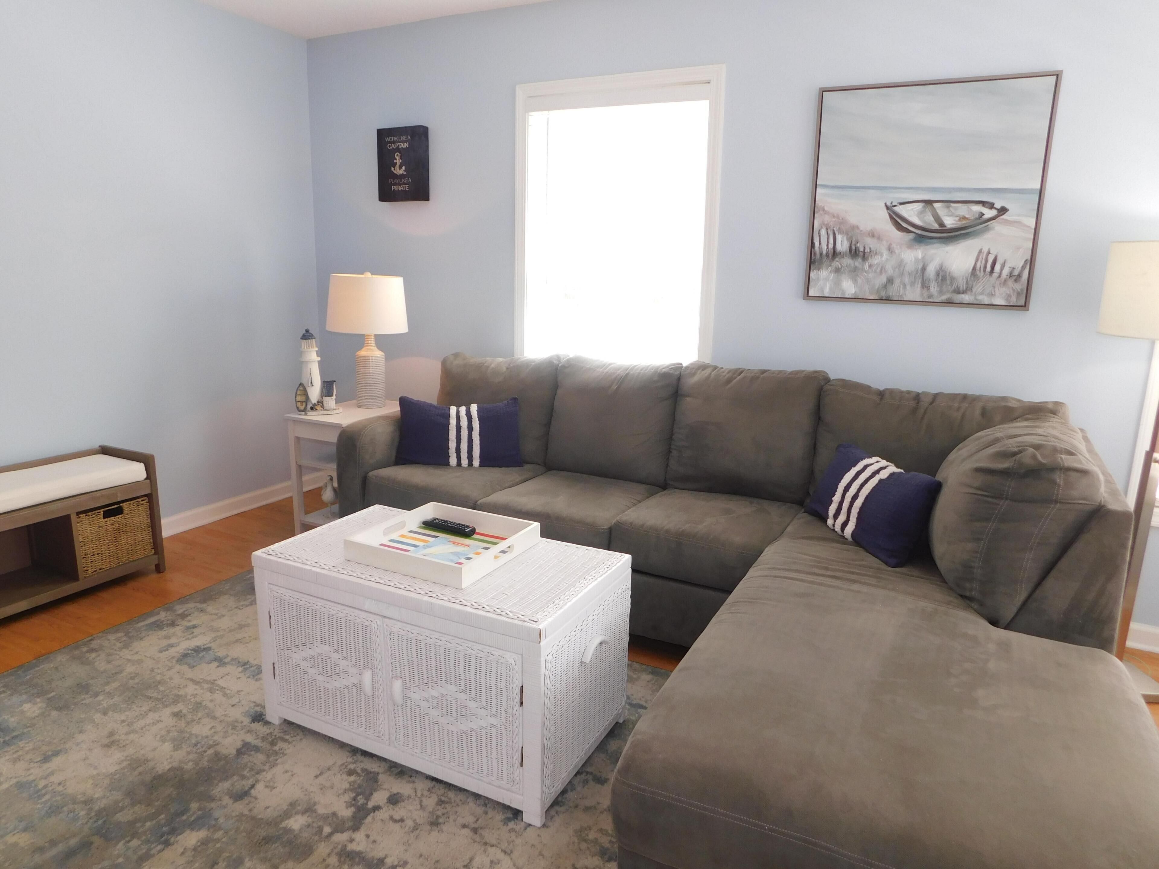 A living room with a grey sofa, a white coffee table, a lamp, and a painting on the wall.