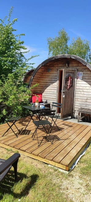 En træhytte med veranda, et bord med stole og en lille terrasse.