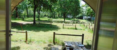 An open archway leading to a picnic table set outdoors with a view of a grassy area and trees.