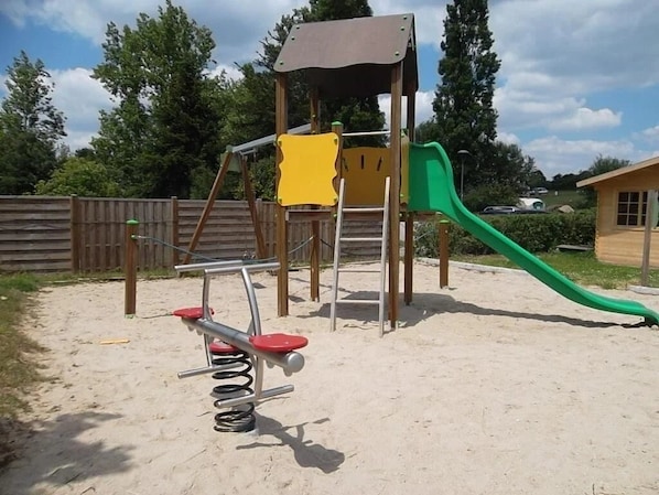 Ein Spielplatz mit Rutsche, Schaukeln und einer Kletterkonstruktion.