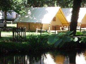 A campsite with tents, a wooden fence, and a body of water.