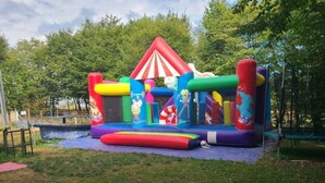 Eine farbenfrohe, aufblasbare Spielkonstruktion mit Rutsche, Hüpfbereich und einem kleinen, abgeschlossenen Bereich mit einer Zeichentrickfigur.