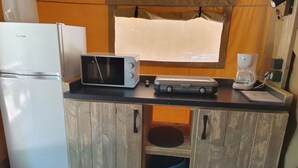 Eine Küchenzeile mit einem weißen Kühlschrank, einer Mikrowelle, einer Kaffeemaschine und Holzschränken.