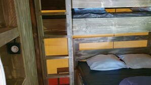 Ein Stockbett mit Holzrahmen, einer Matratze und Kissen.