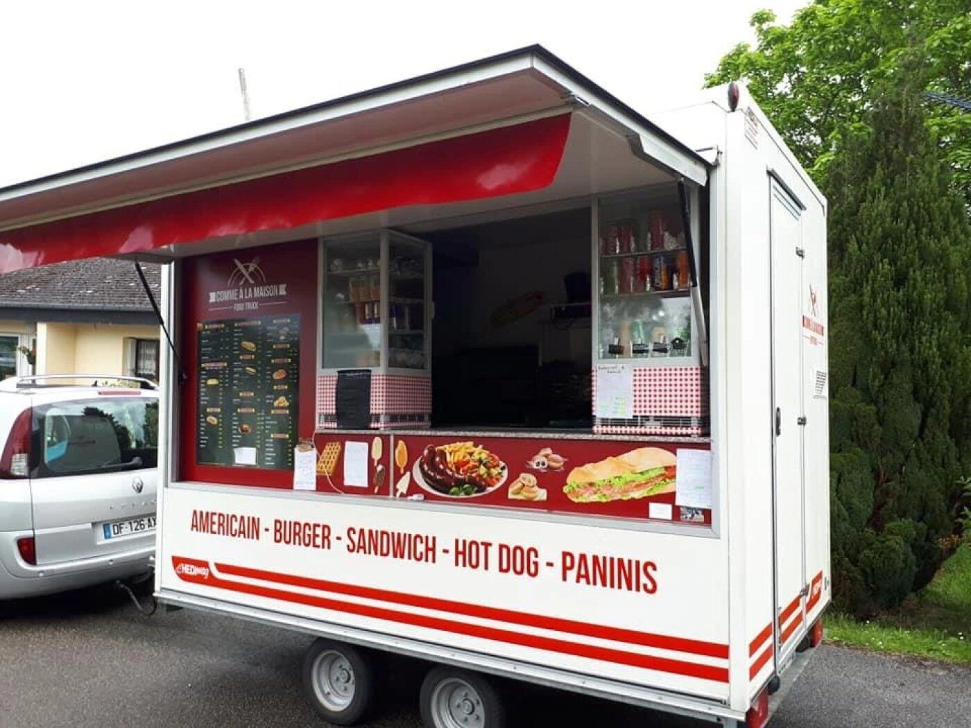 A food truck with a menu displaying items like American, burger, sandwich, hot dog, and paninis.